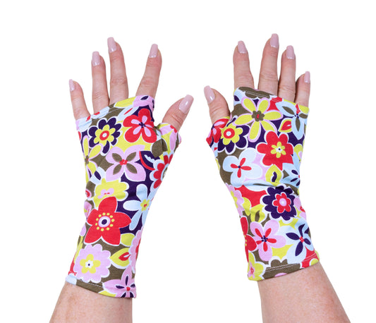 rechte und linke Damenhand mit Pulswärmer, Handstulpen, Handschuhe ohne Finger mit lackierten Fingernägel, Stoff ist knallbunt geblümt. Die beiden Hände befinden sich mitten groß im Bild
