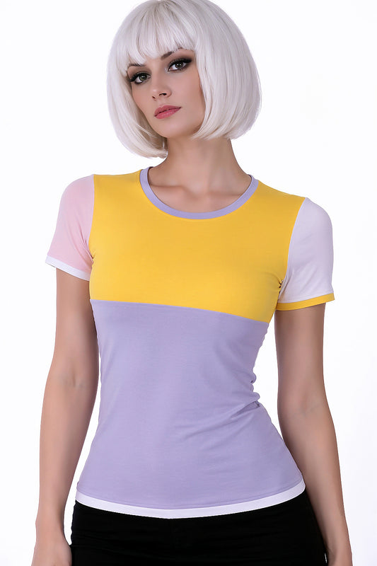Valentina trägt Nikita kawaii Serie in pastelligen, hellen Tönen: colorblock shirt frontal von vorne, Kopf leicht zur Seite geneigt, das Oberteil hat die Größe 34 und die Farb-Kombination: rosa, flieder, gelb, weiss. Vorderteil ist aufgeteilt in 2 colorblocks: oben die Passe in gelb, Rundhals mit Paspel in flieder; unterer colorblock unterhalb der Brust beginnend in flieder, Paspel weiß; ein Ärmel weiß mit gelber Paspel, anderer Ärmel rosa mit weißer Paspel, aus Baumwolle, Handarbeit