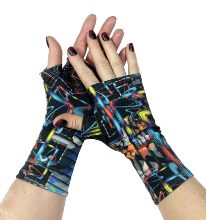 ein Paar Handstulpen ohne Finger an Damen Händen fotografiert, sehr stylisch mit lackierten Fingernägeln in der Farbe der Handschuhe: blau, schwarz bunt. Stoff von Stenzo, abstrakt digital multi Muster