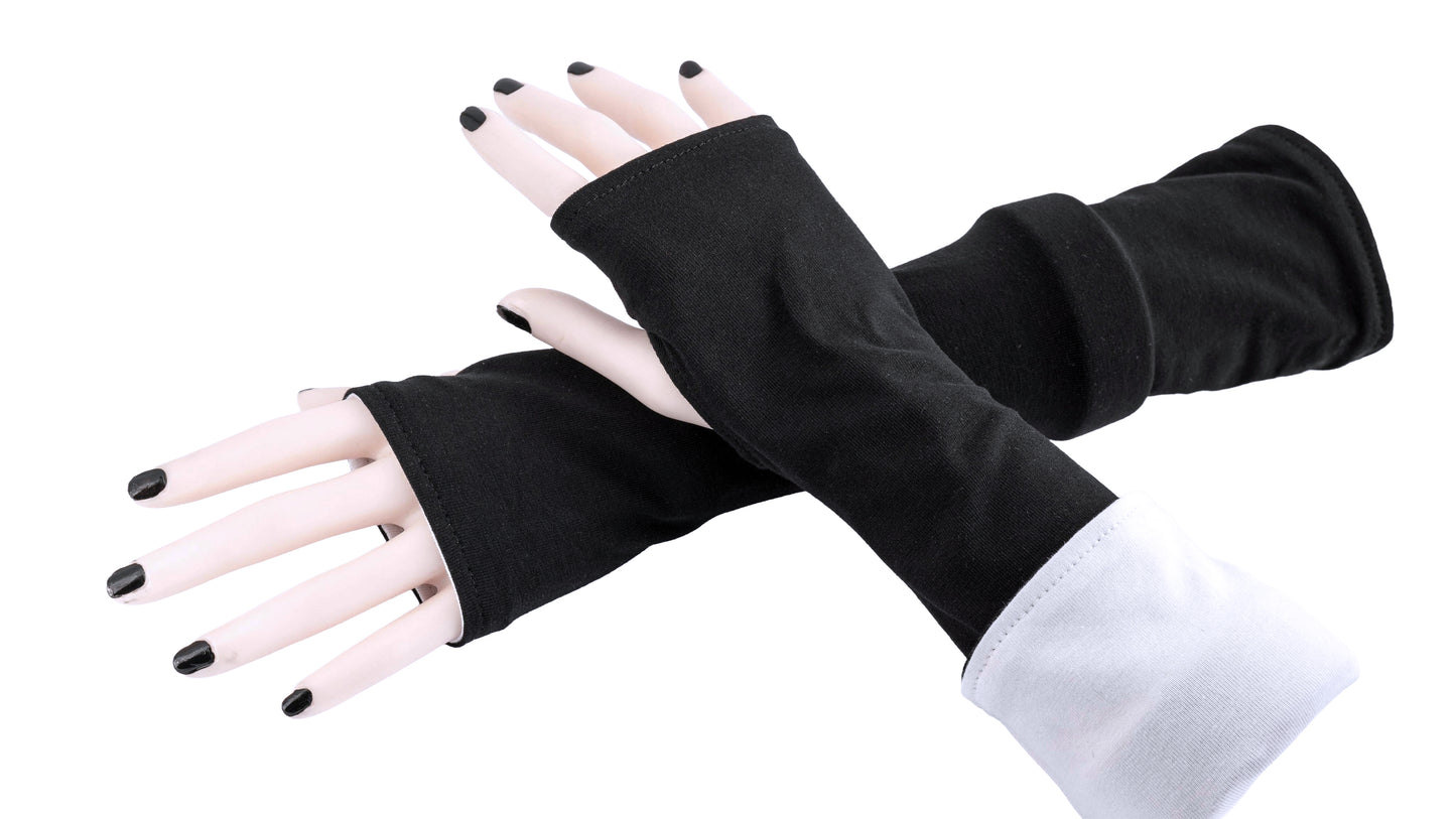 andere Ansicht der Armstulpen in schwarz weiß. Ein paar Damen Arme und Hände übereinander tragen Mouska Alfars Original Stulpen, umgekrempelt. Es gibt verschiedene Tragemöglichkeiten. entweder zwei verschiedene Farben oder beide Farben gleich, umgekrempelt oder lang.