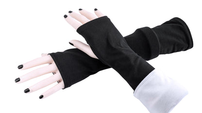 andere Ansicht der Armstulpen in schwarz weiß. Ein paar Damen Arme und Hände übereinander tragen Mouska Alfars Original Stulpen, umgekrempelt. Es gibt verschiedene Tragemöglichkeiten. entweder zwei verschiedene Farben oder beide Farben gleich, umgekrempelt oder lang.