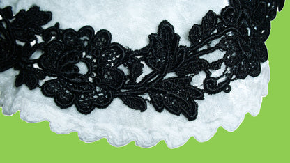 Detail von der schwarzen Blumen Borte auf dem weißen Samt.