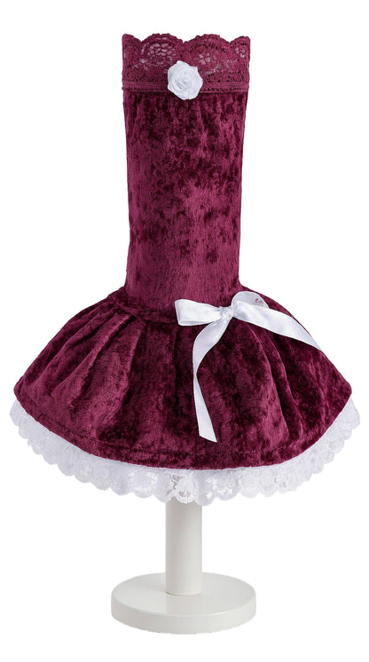 Armstulpe einzeln auf einem Fuß präsentiert. Viktorianischer Stil, Manschetten Stulpe mit zwei angenähten Röckchen in bordeaux rot und weiß, mit Wäsche spitzen, Zierspitzen, elastischer Abschluss-Spitze verziert sowie Satin Schleife und Rose. Bauschige Röckchen. Der Fuss ist weiß, Hintergrund auch. Studiobeleuchtung. Material ist Pannesamt und Baumwolle.
