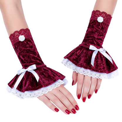 ein Paar kawaii aesthetic, gothic lolita, Cosplay Armstulpen nebeneinander liegend an Damen Händen fotografiert. Sie bestehen aus 3 Teilen: einem Manschettenteil und 2 Lagen Röcken, alles aus Pannesamt, der Unterock ist aus Baumwolle mit Zierspitze verziert. Am Manschetten Teil eine elastische Abschluss-Spitze, mittig mit Satinrose und seitlich auf dem Rockteil eine Satinschleife. Jeweils gegengleich bei den beiden Stulpen. Farbe bordeaux schnee weiß