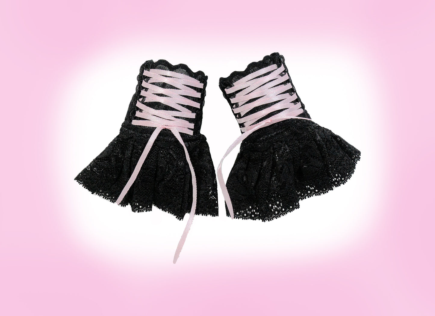 Sweet Lolita Manschetten aus Spitze in schwarz mit Zier-Schnürung & Röckchen für Cyber, Punk, Harajuku, Gothic Outfits. Handgefertigt in Deutschland. Hohe Qualität. Super Preis-Leistungs-Verhältnis. Keine billige China Ware. Die kleinen Schätze sind flatlay flach liegend nebeneinander fotografiert auf einem Rosa Hintergrund mit weißem Schatten. Die Schnürung schnürt sich mit einem schmalen Satinband wie ein Bondage vom Manschetten-Teil zum Röckchen hinunter.