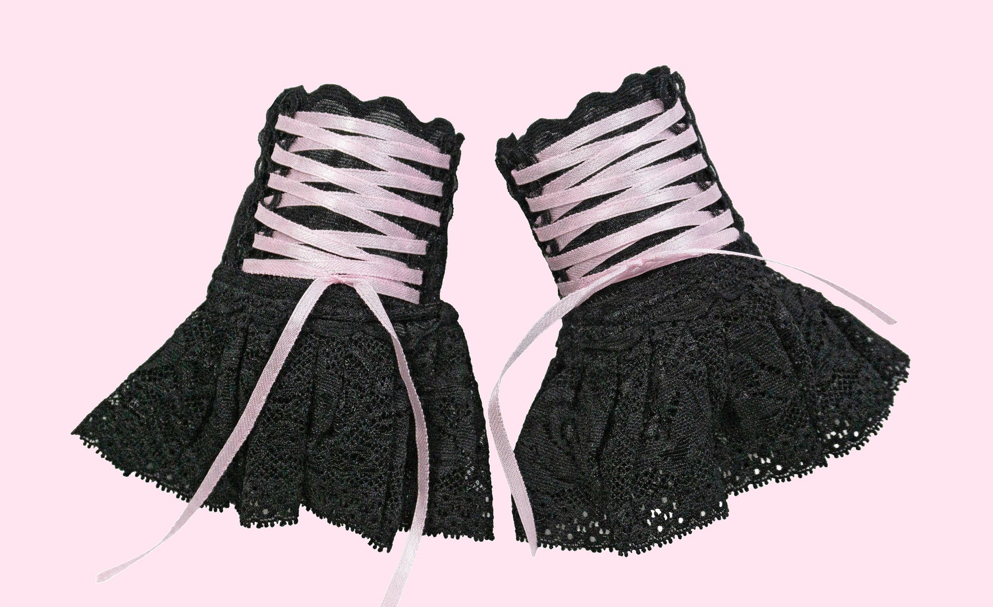 ein weiteres Paar Damen Pulswärmer mit Röckchen im Punk und Gruftie Stil, frei an der Wand stehend abgelichtet, auf baby rosa Hintergrund mit Studio Licht. Hier kann man die Details gut sehen. Sie stehen friedlich nebeneinander und warten auf Ihren Besitzer. Fair & Slow Fashion direkt aus Deutschland. Auf Bestellung in 7 Größen möglich.