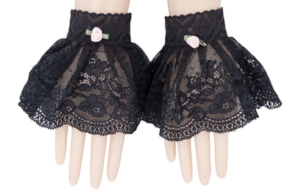 mini Stulpen Manschetten bestehend aus Spitzenband mit Röckchen angenäht. An zwei Puppenhänden dargestellt. Netz-Spitze mit Musterung und kleiner rosa Rose verziert. Ideales Dark Styles Accessoire für Punk & Gothic Outfits. Auch als Geschenk + Mitbringsel. Von hoher Qualität, aus asiatisch gemusterter Spitze, deutsche Produktion. Gute Passform, gerafftes Rockteil. Farbe schwarz. Manufaktured in Hamburg. 