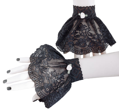 ein paar gothic Manschetten an Damen Händen präsentiert, schwarz lackierte Fingernägel. Hintergrund Studio weißes ambiente. Mini Stulpen in schwarz mit Röckchen schwingend. Eine Stulpe an der Wand stehend, die andere liegend. Handarbeit aus Hamburg, Deutschland von Mouska Alfar Modedesign für Harajuku und Darkfashion.