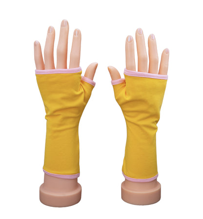 ein Paar Handschuhe ohne Finger an Händen präsentiert, farbe in sonnen gelb und gefüttert mit rosa. Aus Baumwolljersey