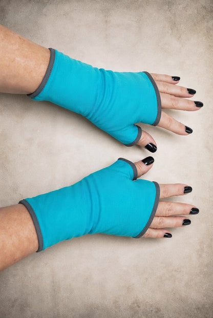 fingerlose Handschuhe von Mouska Alfar: an Damen händen fotografierte tuerkis farbene Handwaermer, die Hände sind nebeneinander gelegt in die Mitte des Fotos und seitlich auf dem Bild, um eine andere Perspektive zu haben. Man erkennt gut die Proportionen und Länge, in Etwa 19 cm reichen knapp an die Fingerknöchel und übers Handgelenk. Futter mausgrau, grau. Futter stehen 24 Farben zur Wahl und Größen 7 von kleine bis große Hände, alles dabei. Nur auf Bestellung