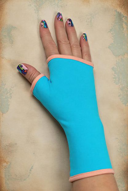 Einzel Basic Handschuh ohne Finger, fotografiert an einer Damenhand, die auf dem Tisch liegt. Bunt lackierte Fingernägel, sehr stylisch und exklusiv. Hintergrund Vintage Ambiente in taupe. Aus Baumwolle Jersey mit Paspel, gefüttert. Oberstoff türkis, Futter pfirsich. 
