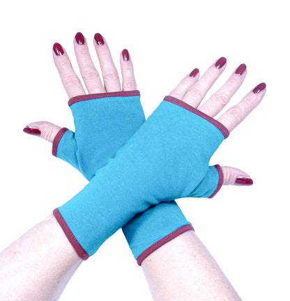 fingerlose Handschuhe von Mouska Alfar Harajuku Mode Design aus Hamburg, Deutschland: an Damen händen fotografierte tuerkis farbene Handwaermer, die Hände sind übereinander gelegt in die Mitte des fotos. So sieht man gut die Proportionen und Länge, in Etwa 19 cm reichen knapp an die Fingerknöchel und übers Handgelenk. Futter dunkel rot, bordeaux