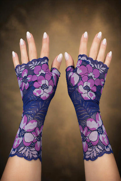 ein Paar lange Handschuhe in lila blau Tönen neben einander auf dem Foto anhand von Damen Händen fotografiert. Sie sind vom Grundtenor dunkelblau-violett mit riesigen Blumen. Aus Wäschespitze gearbeitet, satte Farben.