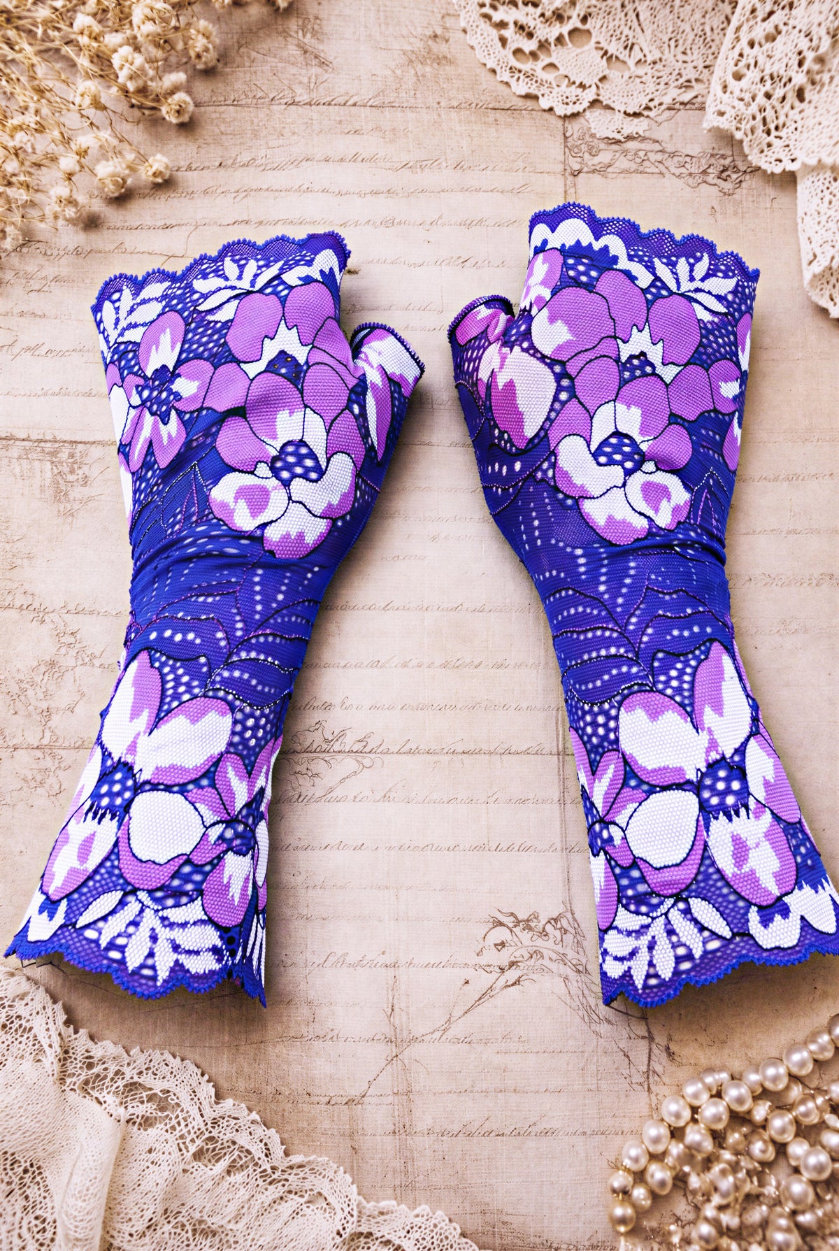 ein Paar Damen Spitze Handschuhe fingerlos mit großen Blumen in violett lila magenta liegen in flatlay mitten im Bild auf Vintage Ambiente Hintergrund.
Handarbeit Hippie Boho Handschmuck