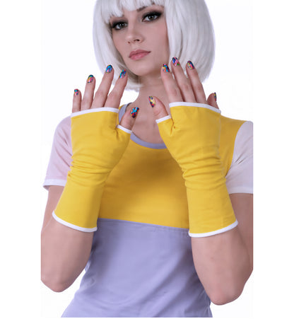 Handschuhe fingerlos colorblock design mit Futter und fake Paspel, eng anliegend, satte Farben, aus Baumwolle, Handarbeit von Mouska Alfar. Hauptfarbe sonnen gelb, Futterfarbe wählbar. Hier Futter in weiß, präsentiert von Model Valentina mit beiden Händen zeigt sie ins Bild, mit bunt lackierten Fingernägeln und das passende Nikita Shirt dazu