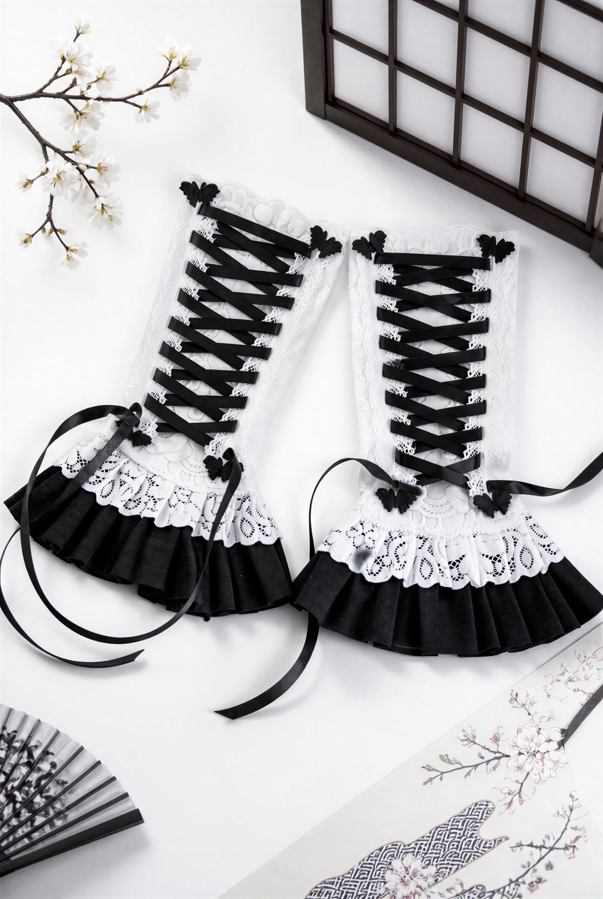 ein paar Gothic Lolita Armstulpen mit Bondage Schnürung, Schmetterlingen & Spitzen Röckchen. Sehr bequem und stylisch. Sie liegen in einem japanischen Ambiente flatlay im Bild, die Schnürung ist nicht zu einer Schleife gebunden, damit man die Schmetterlinge links und rechts daneben besser sehen kann. Sie sind für Damen gedacht.