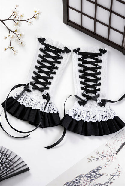 ein paar Gothic Lolita Armstulpen mit Bondage Schnürung, Schmetterlingen & Spitzen Röckchen. Sehr bequem und stylisch. Sie liegen in einem japanischen Ambiente flatlay im Bild, die Schnürung ist nicht zu einer Schleife gebunden, damit man die Schmetterlinge links und rechts daneben besser sehen kann. Sie sind für Damen gedacht.