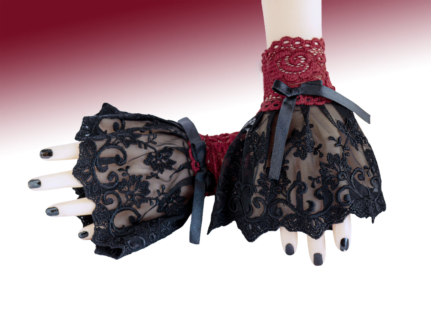 Manschetten aus Spitze in schwarz rot, fotografiert an einem Paar Damen Hände, die übereinander liegen. Schwarz lackierte Fingernägel. Kleine Armstulpen mit Schleife aus Satin verziert, Handgefertigt in Deutschland. Sehr hohe Qualität. Gesamte Produktionskette vor Ort in Deutschland.