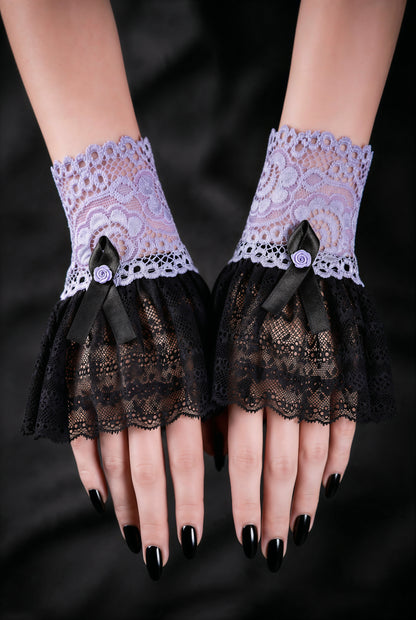 Sweet Lolita Gothic Manschetten aus Spitze in flieder schwarz, fotografiert an einem Paar Damen Hände, die auf schwarzen Stoff nebeneinander liegen. Schwarz lackierte Fingernägel. Kleine Armstulpen mit Satin Rose verziert, Handgefertigt in Deutschland.