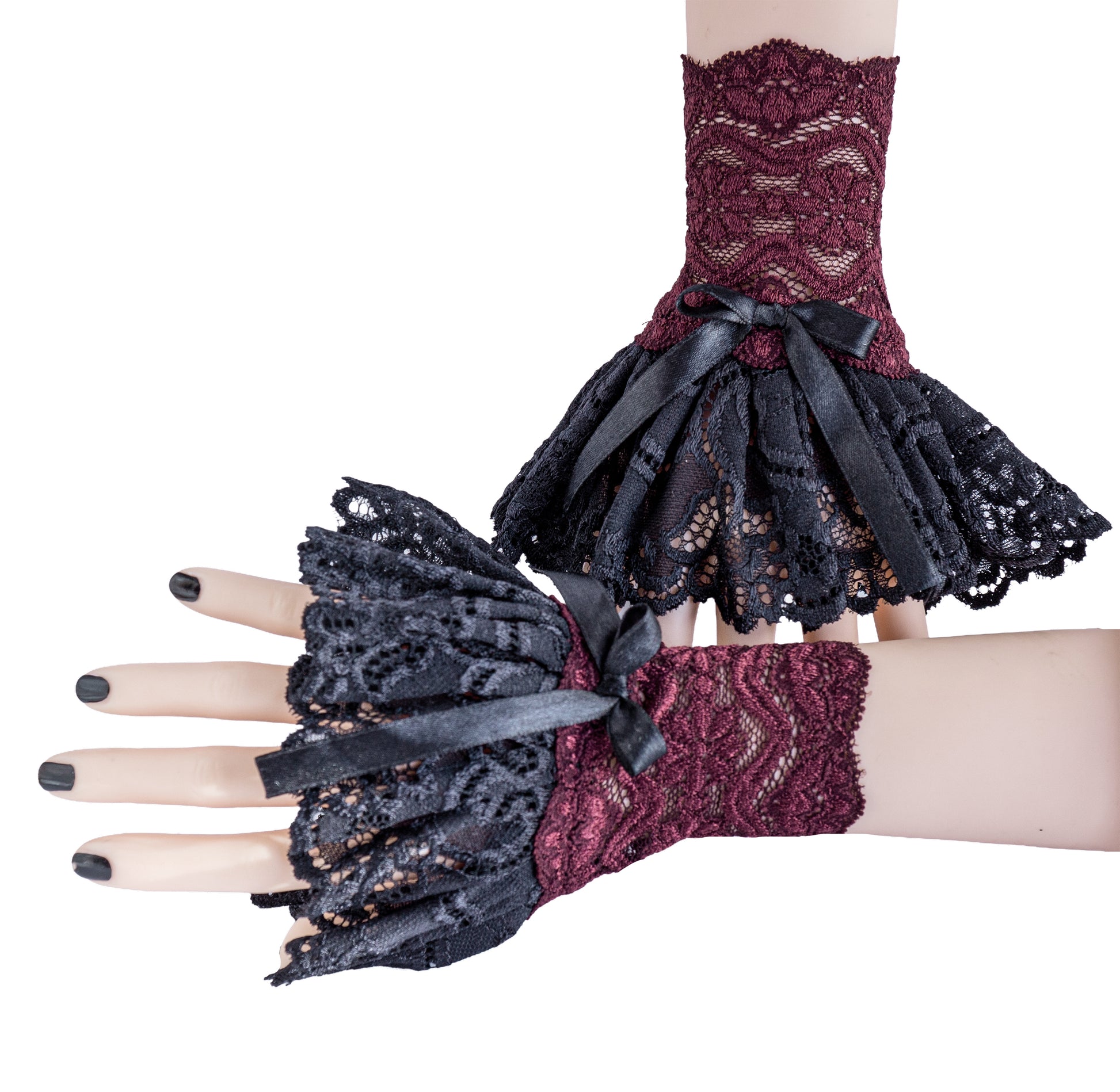 ein paar gothic Manschetten an Puppen Händen mit lackierten Nägeln präsentiert. Eine Hand liegt vor der anderen. Die andere Hand steht aufrecht an der Wand. Hintergrund Studio, weiße Beleuchtung. Stulpen sind ein handgefertigtes Unikat von Mouska Alfar, in Deutschland hergestellt. Stoff reicht nur begrenzt. Daher nur wenige Exemplare verfügbar.