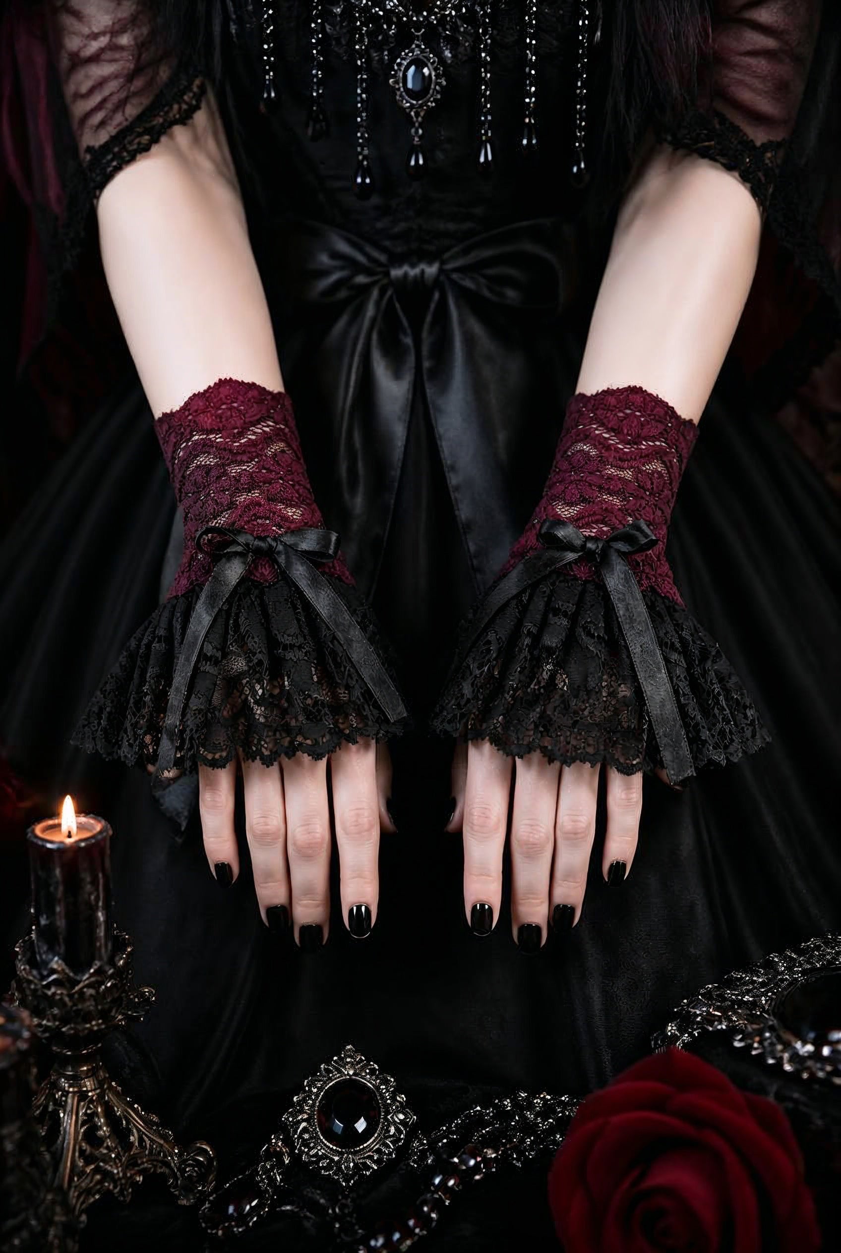 ein paar gothic Manschetten an Damen Händen präsentiert, Hintergrund gothic vampir ambiente. Stulpen in schwarz bordeaux-rot mit ausladendem schwingenden Röckchen und manschetten teil mit satin schleife verziert.