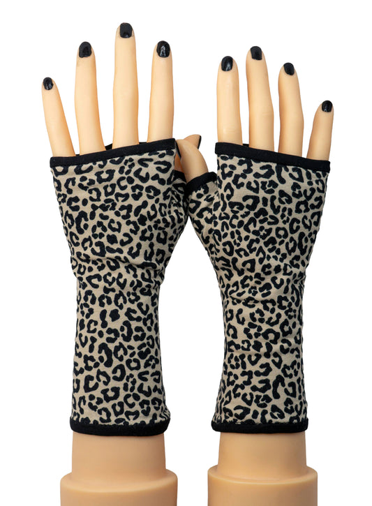 Ein Paar fingerlose Handschuhe mit Leopardenmuster in Schwarz und Beige. Die Handschuhe haben eine schwarze Paspel, gefüttert und werden auf Schaufensterpuppenhänden mit schwarzem Nagellack präsentiert. Sie sind aufwändig genäht, in allen größen erhältlich, handarbeit