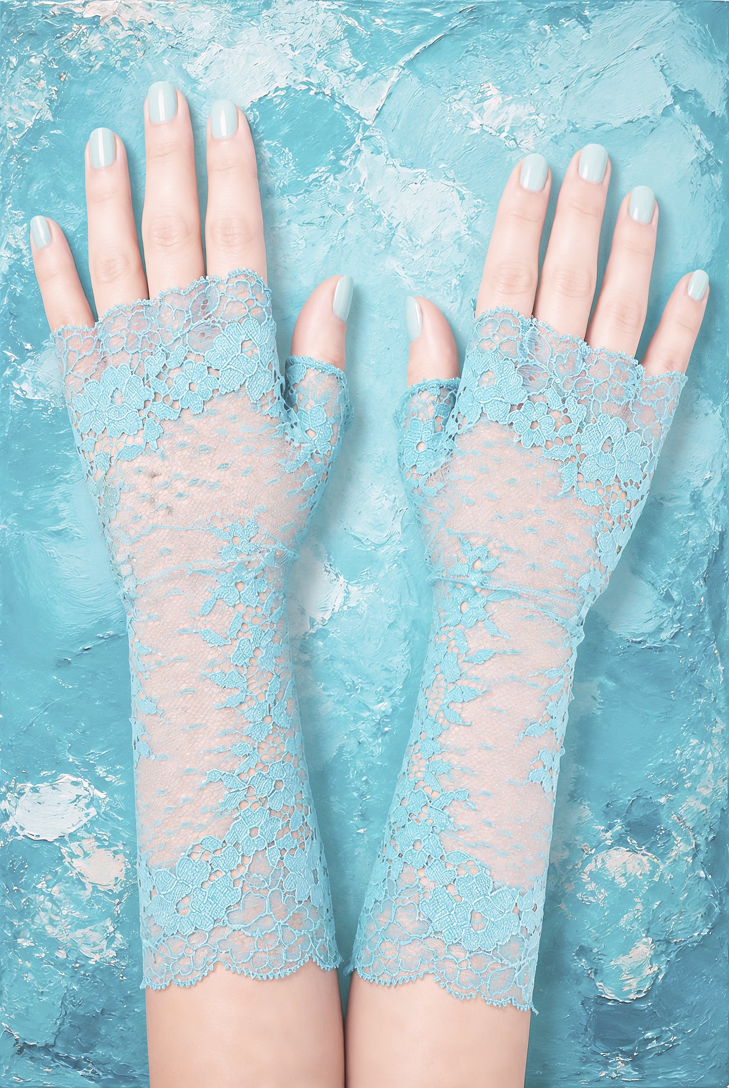 zarte und feminine Handschuhe ohne Finger, lang in türkis mit floralem Design, sehr sinnlich, romantisch, weiblich und Vintage. Ein edles, nobles Accessoire bei super günstigem Preis-Leistungs-Verhältnis. Auf diesem Foto liegen die Stulpen, angezogen auf Damen Armen, auf dem Tisch, welcher mit nostalgischem türkis farbigen Stoffen ausgelegt ist - was dem Foto einen ganz besonderen Charme verleiht,
