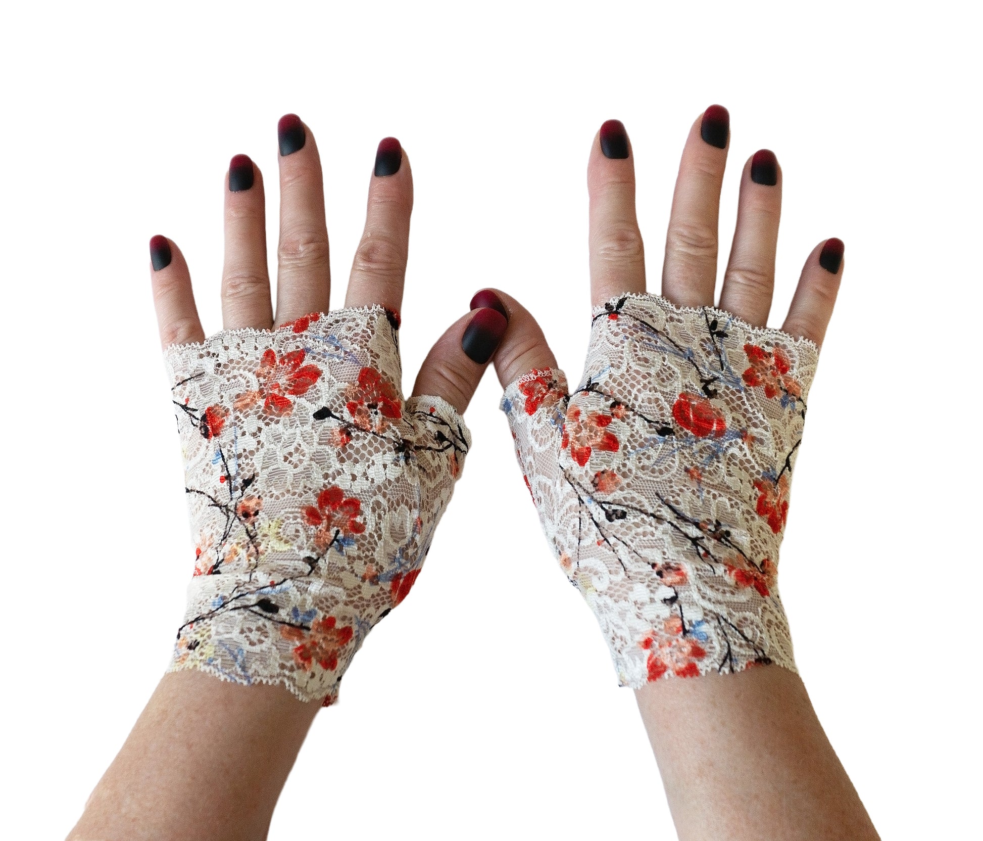 ein paar Handschuhe ohne Finger an Damenhänden fotografiert, man sieht die ganzen Hände frontal, lackierte Fingernägel. Sie sind aus Spitze gefertigt im japan Stil mit Kirschblüten, Sakura auf weißem Grund. Eine rechte und eine linke Hand.