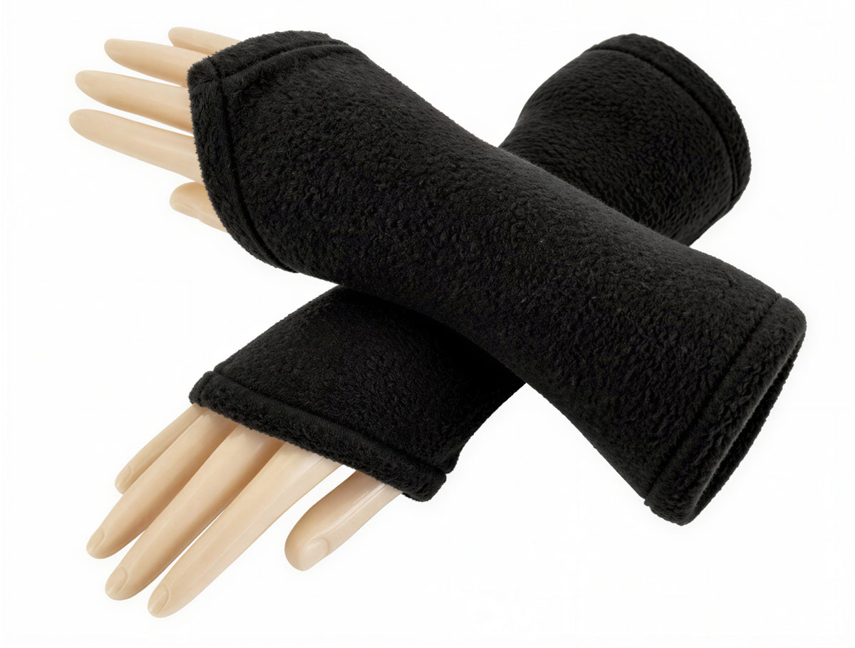 ein Paar flauschige Wichtel Armstulpen aus Fleece in uni schwarz, an übereinander gelegten Modell Armen fotografiert, unlackierte Fingernägel. Die Stulpen sind halblang und nach vorn über den Handrücken wichtelig zugeschnitten, sie sind fluffig, pflegeleicht, robust und langlebig bei guter Pflege.
