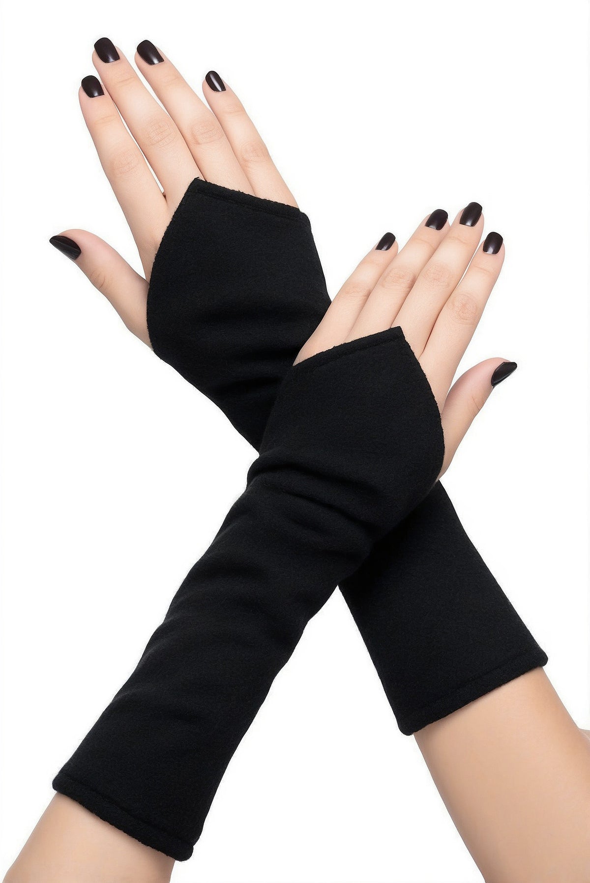 ein Paar flauschige Wichtel Armstulpen aus Fleece in uni schwarz, an übereinander gelegten Damen Armen und Händen fotografiert mit schwarz lackierten Fingernägel. Die Stulpen sind halblang und nach vorn über den Handrücken wichtelig zugeschnitten, sie sind fluffig, pflegeleicht, robust und langlebig bei guter Pflege.