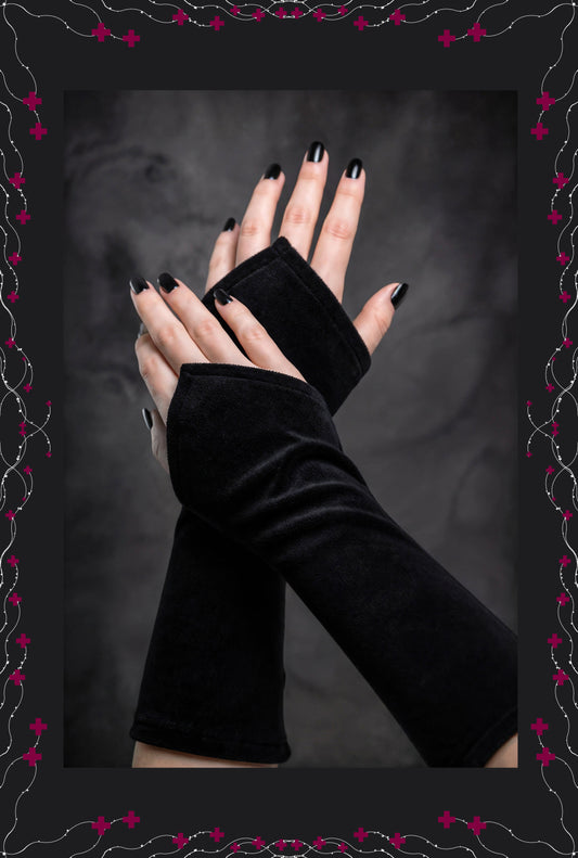 ein paar schwarze Nicki Samt Velour Wichtel Stulpen, an Damenhänden fotografiert, die mittig im Bild übereinander liegen. Dunkles gothic dark ambiente im Hintergrund, sehr stylisch.