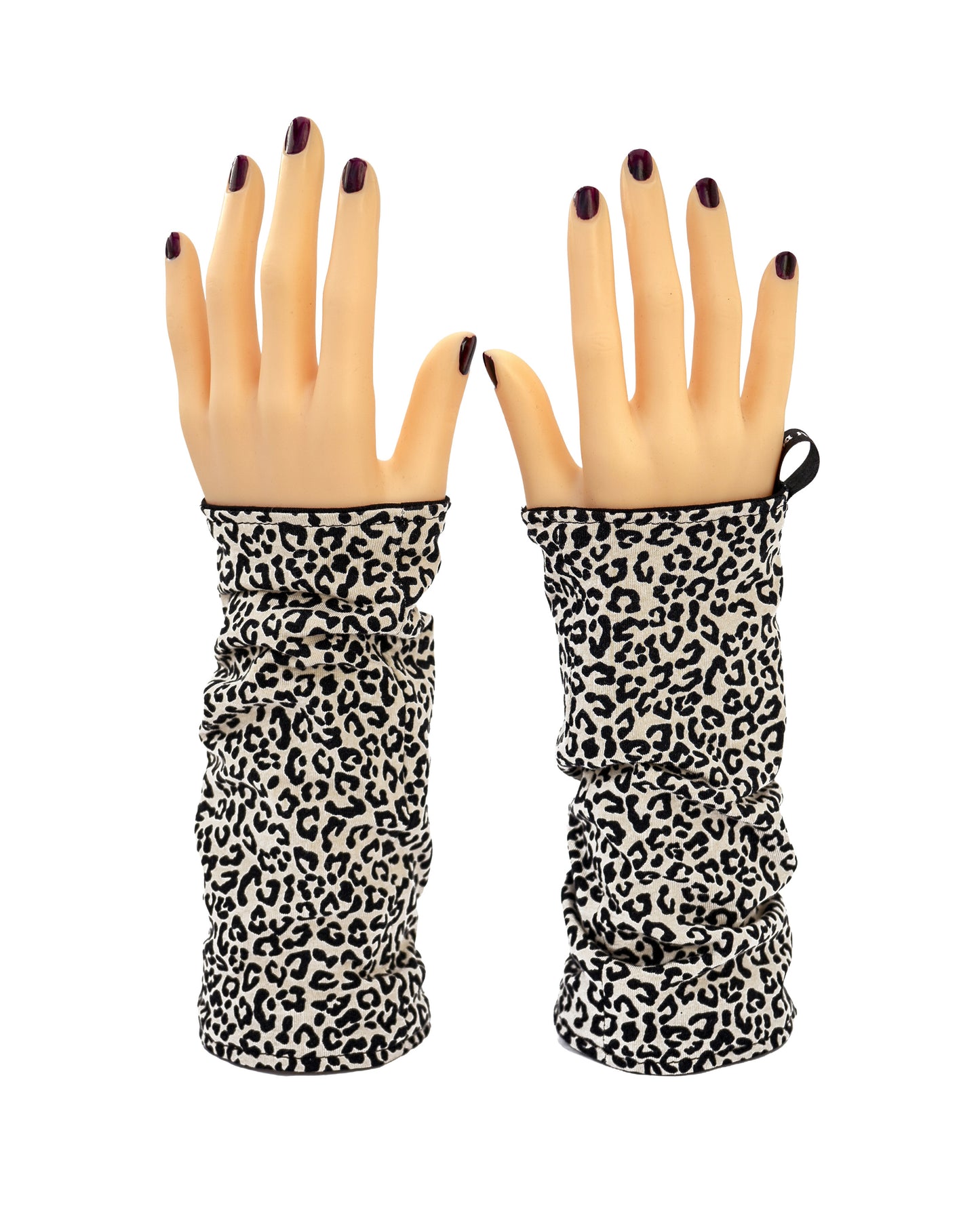 ein paar leopard print Baumwolle Armstulpen, kurze Variante, fotografiert an Modelhänden, die auf dem Tischstehen. Verschiedene Trage Möglichkeiten: hier beide Arme mit der Leo Seite oben, Futter schwarz.