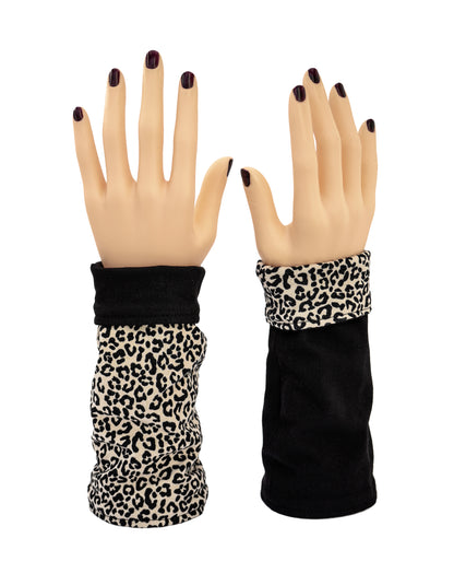 ein paar leopard print Baumwolle Armstulpen, kurze Variante, fotografiert an Modelhänden, die auf dem Tischstehen. Verschiedene Trage Möglichkeiten: hier umgekrempelt, eine Seite leo, schwarz und der andere Arm schwarz mit Leo umgekrempelt